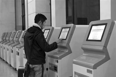 昨日，北京站东售票厅，市民在自动取票机上刷身份证领取在网上预订的车票。本报记者 孙纯霞 摄